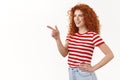 Interesting what is it. Intrigued charismatic half-turned redhead curly woman check out cool offer pointing looking left