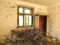 The interior of an abandoned old rural house with light cracked walls, an old beautiful window with broken glass and a floor
