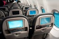 The interior of the aircraft. Empty airplane cabin. Rows of passenger seats with screens in the head restraints