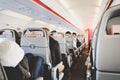 Interior of airplane in economy class with passengers sitting on seats, low cost airline, travel concept