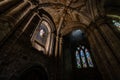 Interior of an ancient stone cathedral with arches and strained glass.