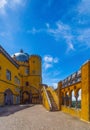 Interior of the arched courtyard with stone stairs and the yellow painted walls of the Pena Palace, under a sunny blue sky for Royalty Free Stock Photo