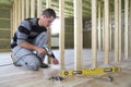 Interior of attic insulated room with oak floor under reconstruction. Young professional worker uses level and screwdriver Royalty Free Stock Photo