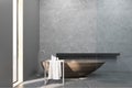 Interior of a bathroom with a narrow window, wooden tub, concrete walls and a long shelf.