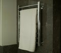 A white towel hangs on a metal towel in a dark bathroom. The interior of the bathroom is the room`s room Royalty Free Stock Photo