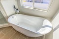 Interior of a bathroom with a smooth and glossy bathtub in th corner