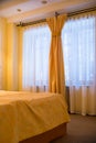 interior of bedroom with big window with orange and white curtains. Comfortable bed,modern style. Room in apartment in Royalty Free Stock Photo