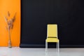 Interior of a black and orange room with colored chairs, armchairs