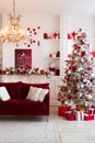 Interior of bright modern living room with fireplace, chandelier and comfortable sofa decorated with Christmas tree and Royalty Free Stock Photo