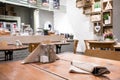 Interior of cafe showing laid wooden tables with cutlery in shabby chic rustic styled eating area