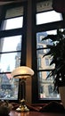 The interior of the cafe. Vintage table lamp lit by soft yellow light against the background of a large window.