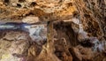 Interior of a cave, with a large pillar of stalactites and stalagmites