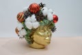 Festive Christmas accessories - red balls, fir cones and cotton on a stylized golden female head. Interior Christmas composition