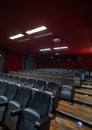 Interior of a cinema hall with projector handing on the ceiling, Empty cinema hall seats, comfortable and soft chairs. Perspective Royalty Free Stock Photo