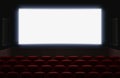 Interior of a cinema movie theatre with shiny white blank screen. Red cinema or theater seats in front of the screen Royalty Free Stock Photo