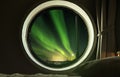 Interior circle window in bedroom with beautiful Northern lights Aurora Borealis view at night Royalty Free Stock Photo