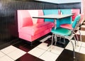 Interior of a classic American 1950s style diner with colorful stools and checkered floor