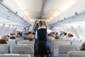 Interior of commercial airplane with stewardess serving passengers on seats during flight. Royalty Free Stock Photo