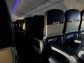 Interior of commercial airplane with unrecognizable passengers on their seats during flight shot from the rear of airplane. Royalty Free Stock Photo