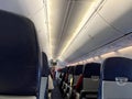 Interior of commercial airplane with unrecognizable passengers on their seats during flight shot from the rear of airplane. Royalty Free Stock Photo