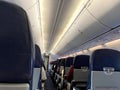 Interior of commercial airplane with unrecognizable passengers on their seats during flight shot from the rear of airplane. Royalty Free Stock Photo