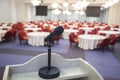 Interior of a conference room. Detail of a microphone sitting on a desk facing the room full of tables and chairs Royalty Free Stock Photo