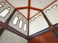 Interior corner with arched windows, Arabic calligraphy, and decorative beams in red and gold. Royalty Free Stock Photo
