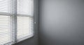 Interior Corner with White Horizontal Blinds Covering a Window and a Plain Gray Wall Royalty Free Stock Photo
