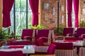 Interior of a cozy urban cafe with soft comfortable chairs in red colors with brick walls