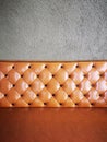 Vintage orange or brick colour leather sofa with grey concrete wall background. Royalty Free Stock Photo