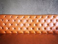 Vintage orange or brick colour leather sofa with grey concrete wall background. Royalty Free Stock Photo