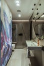 Interior design of bathroom interior with colorful wallpaper, big mirror, silk, toilet seat, shower, gray tiles, modern lamp, vase