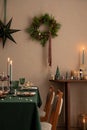 Interior design of Christmas dinning room interior with table, christmas wearth, candle, brown wall, star on wall, candle with