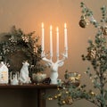 Interior design of christmas living room interior with wooden console, stylish candlestick with candle, christmass tree and