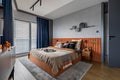 Interior design of elegant bedroom with big orange bed, beige and grey bedclothes, blue curtain, rug, modern lamp, night stand,