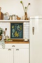 Interior design of kitchen space interior with mock up poster frame, fridge, jar with spices, pear, vase with flowers, kitchen