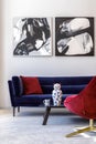 Interior design of living room with blue velvet sofa, red armchair, paintings, design vase, table, decoration, concrete floor. Royalty Free Stock Photo