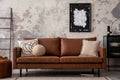 Interior design of loft industrial apartment with mock up poster frame, modern brown sofa, beige pillows, black commode and Royalty Free Stock Photo