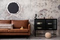 Interior design of loft industrial apartment with mock up poster frame modern brown sofa, black commode, round pillows and Royalty Free Stock Photo