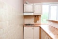 Interior design of modern narrow smart compact kitchen with white contemporary furniture, beige ceramic tiles on wall Royalty Free Stock Photo