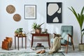 Interior design of retro living room with stylish vintage armchair, shelf, house plants, cacti, decoration, two mock up frames. Royalty Free Stock Photo