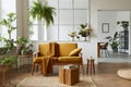 Interior design of scandinavian open space with yellow velvet sofa, plants, furniture, book, wooden cube and personal accessories