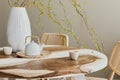 Interior design of stylish dining room interior with family wooden and epoxy table, rattan chairs, flowers in vase and teapot. Royalty Free Stock Photo