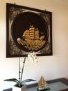 Interior Design. On the wooden table was a pot of orchids and a boat ornament and the wall hung a wooden frame with a gold