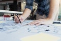 Interior designer or architect reviewing blueprints and holding pencil drawing on desk at home office Royalty Free Stock Photo