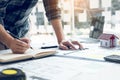 Interior designer or architect reviewing blueprints and holding pencil drawing on desk at home office Royalty Free Stock Photo