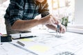 Interior designer or architect reviewing blueprints and holding pencil drawing on desk at home office Royalty Free Stock Photo