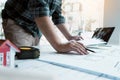 Interior designer or architect reviewing blueprints and holding pencil drawing on desk at home office Royalty Free Stock Photo