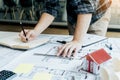 Interior designer or architect reviewing blueprints and holding pencil drawing on desk at home office Royalty Free Stock Photo