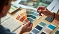 Interior designer chooses color. Designer examines color palettes. Creative process in progress. Hands select color samples.